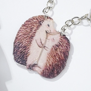 Close-up of interlocking acrylic hedgehog keychains for couples on white background
