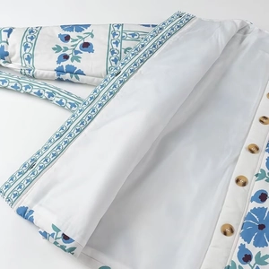 Détail du manteau en coton à fleurs bleues avec boutons marrons et doublure blanche
