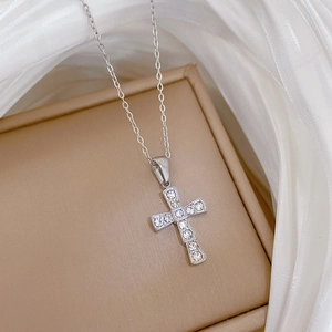 Detail shot of silver titanium steel cross pendant with crystals on a jewelry box