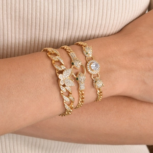 Close-up of golden bangle set with crystal panther and butterfly charms on wrist