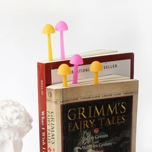 Creative mushroom silicone bookmarks in pink and yellow set on a book against white wall