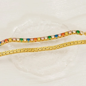 Macro d'un bracelet de tennis en acier doré avec des pierres en zircone multicolores
