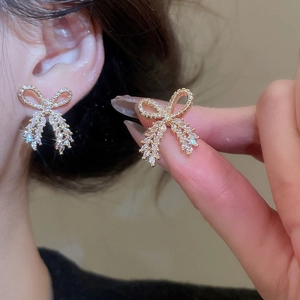 Detail of golden bow-shaped earrings with sparkling marquise and round cubic zirconia stones