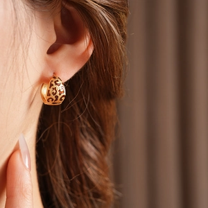 Close-up of woman wearing vintage gold leopard print hollow sphere earrings in high quality