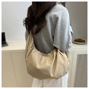Détail du sac croissant plissé beige clair avec tissu texturé et fermeture éclair noire