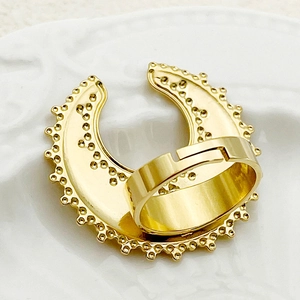 Detail view of gold crescent moon ring with vintage dotted texture on a ceramic dish