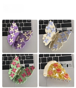 Detailed close-up of butterfly and flower hair claws in purple, white, and green finishes