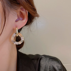 Close-up of gold hoop earrings with inlaid crystal shell accents worn by a model