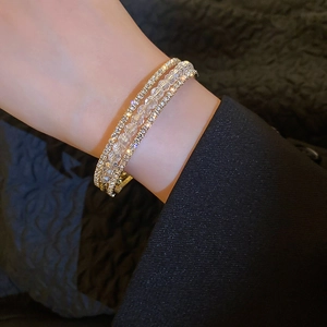 Detail of triple-layered gold alloy bracelet featuring white crystal beads and zircon rows