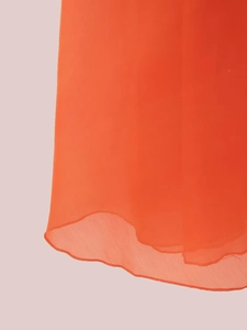 Détail du tissu en mousseline orange vif montrant des couches et des ourlets ondulés