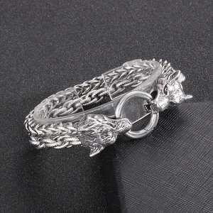 Detail of silver wolf head buckle and double-strand braided metal chain bracelet