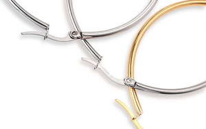 Macro detail of high-polish hoop earrings showing secure hinge closures in gold and silver