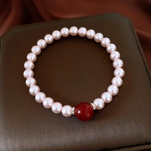Gros plan d'un bracelet de perles avec une perle d'agate rouge et séparateurs argent