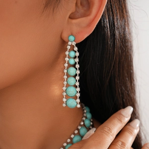 Macro shot of Bohemian style long drop earrings with turquoise stones and white diamonds
