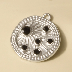 Macro shot of a 304 stainless steel round pendant featuring black crystals and bead edging