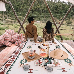 Bohemian geometric camping blanket with ethnic patterns used as a picnic rug in a forest
