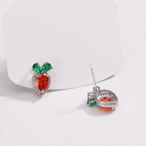 Macro shot of carrot earrings with orange and green gems on silver base setting