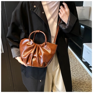 Detail shot of a brown ruched cloud bag featuring glossy PU leather and a slim shoulder strap