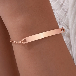 Detailed view of a rose gold curved bar bracelet on a wrist with a delicate chain