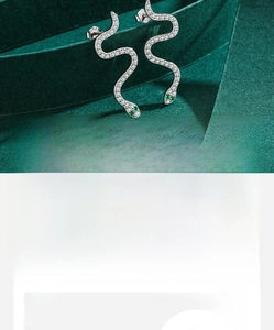 Macro detail of S925 sterling silver snake earrings with pavé zircons and green stone eyes