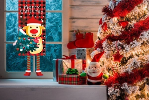 Detail of Christmas reindeer door banner with red plaid patterns near a festive tree