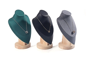 Detailed view of necklace jewelry displays in green velvet, black matte, and gray fabric
