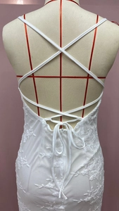 Close-up of white lace dress featuring crisscross back straps and lace-up detail