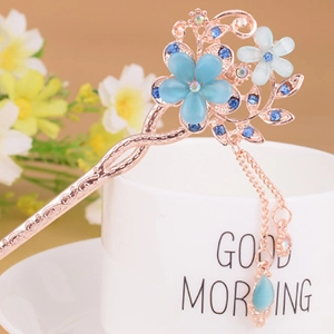 Close-up of flower hair pin with blue cat eye stone and rose gold tassel detail