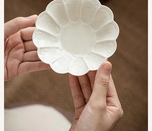 Detailed view of flower-shaped ceramic saucer with exquisite floral embossing