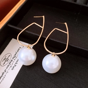 Detail of geometric gold drop earrings with white pearls on black velvet jewelry box