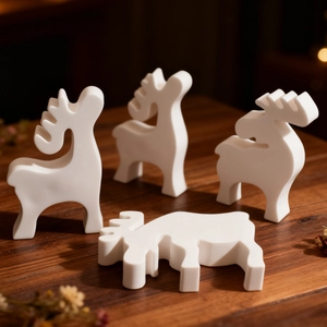 Set of four minimalist white matte Christmas reindeer figurines on a dark wood table