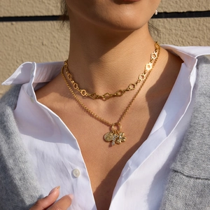 Detail view of 18K gold clover and coin layered necklace set worn by a model