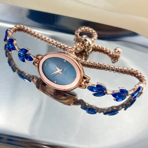 Macro detail of rose gold oval watch featuring blue dial and leaf-shaped gemstones