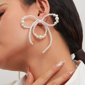 Close-up of model wearing an oversized pearl bow earring with elegant lustrous texture