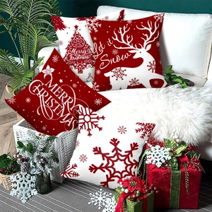 Set of 4 Christmas pillow covers with red reindeer and snowflake patterns on a white sofa