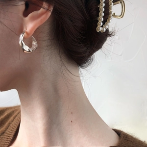 Close-up of elegant silver lava earrings and golden heart-shaped pearl hair claw clip