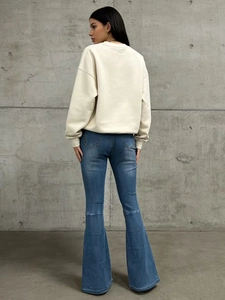Vista posteriore di una modella che indossa jeans svasati blu e una felpa bianca a maniche lunghe