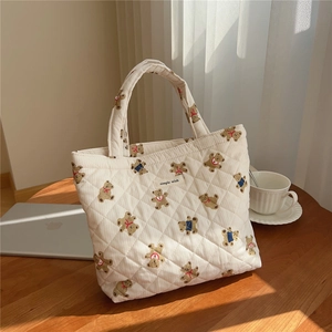 Detail of quilted cotton tote bag featuring cute cartoon bear patterns and a woven label