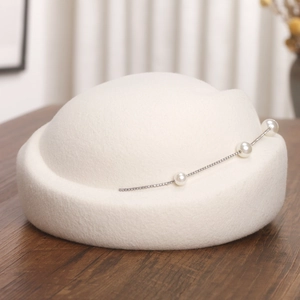 Détail de bibi en laine blanche orné de trois perles et d'une chaîne en strass chic