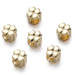 Macro view of six gold clover-shaped beads with a polished finish and center holes