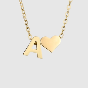 Détail du pendentif cœur et de la lettre A dorée sur une fine chaîne en acier inoxydable