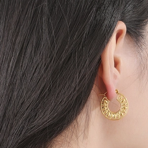 Detailed view of model wearing gold hollow leaf pattern hoop earrings in stainless steel