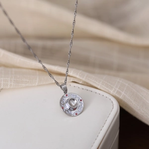 Close-up of a silver pendant necklace with white enamel patterns on a jewelry box