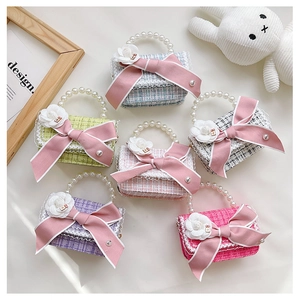 Flat lay of colorful tweed mini bags with pearl handles and pink bow decorations
