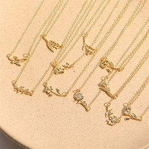 Macro detail of various 18K gold plated floral pendants arranged on a textured round tray