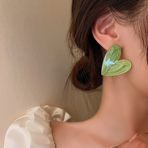 Detail shot of heart-shaped earring with green oil painting texture and gold trim