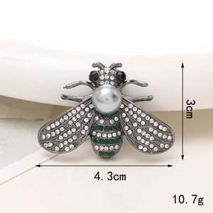 Vista dettagliata dell'accessorio ape argento con strass bianchi e verdi e perla grigia