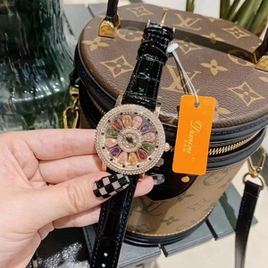 Detail of luxury spinning watch with colorful gemstone dial and black leather strap