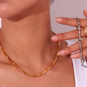 Model wearing gold 3mm cube bead necklace, silver bracelet, and ribbed wide band ring