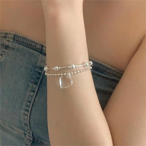 Detailed close-up of double-layer silver beaded bracelet with clear heart charm